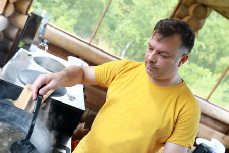 Man takes out mushrooms from cauldron, Kareliaの写真素材