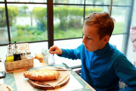Boy eating Adjarian khachapuri in georgian restaurantの写真素材