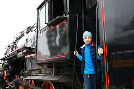 Child on step of steam locomotive at railway station