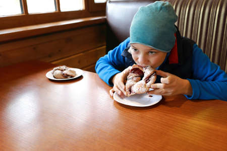 Child eating braided bun with jam in restaurantの写真素材