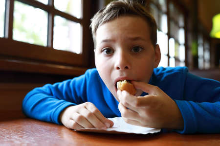 Boy has donut at table in restaurantの写真素材