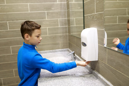 Child washing his hands with soap in restroomの写真素材