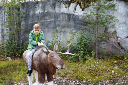 Child sitting on wooden Elk in Ruskeala park, Kareliaの写真素材