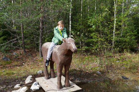 Boy sitting on wooden horse in Ruskeala park, Kareliaの写真素材