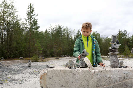 Child folds cairn of stones in italian quarry, Ruskeala, Kareliaの写真素材