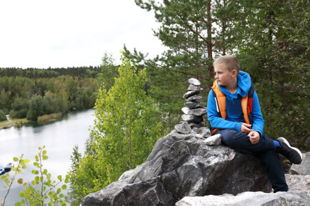 Boy sitting on rock above lake in marble canyon, Karelia, Ruskealaの写真素材