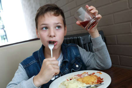 Kid eating french meat with potatoes in restaurantの写真素材
