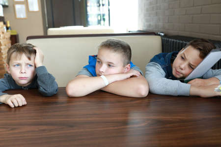 Three hungry children waiting food in restaurantの写真素材