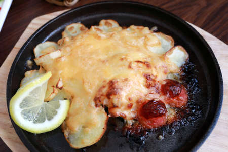 Trout baked with cheese and potatoes on pan in restaurantの写真素材