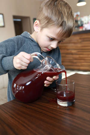 Child pouring juice from carafe in restaurantの写真素材
