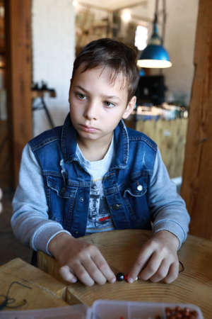 Portrait of serious boy making bracelet at workshopの写真素材