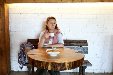 Woman drinking tea with bagels at round wooden tableの写真素材