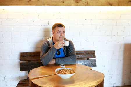 Man drinking tea with bagels at round wooden tableの写真素材