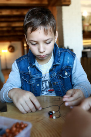 Portrait of kid making bracelet at workshopの写真素材