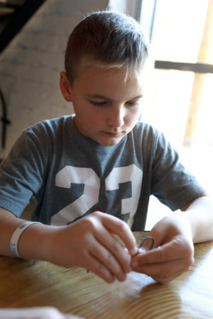 Portrait of serious child making bracelet at workshop