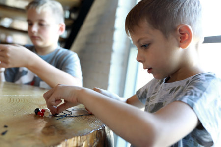 Portrait of two boys making bracelets at workshopの写真素材