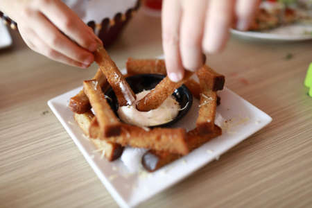 People dipping garlic croutons in sauce in restaurantの写真素材