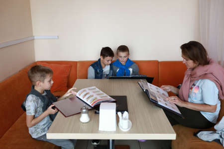Mother with three sons choosing food by menu in restaurantの写真素材