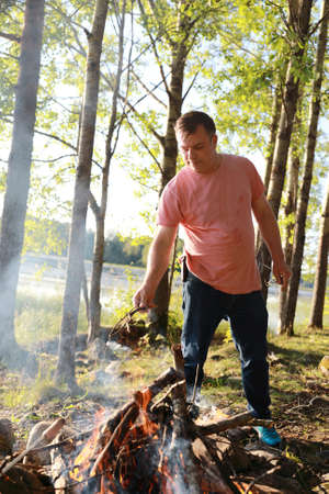 Man lighting bonfire in forest in summer, Kareliaの写真素材