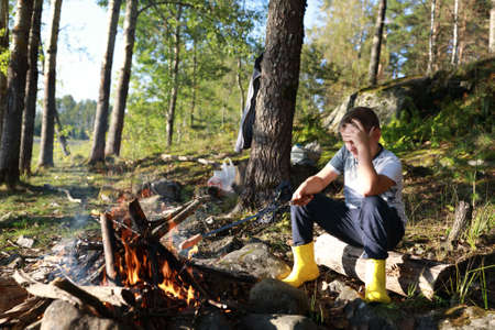 Child frying sausage over fire in forest, Kareliaの写真素材