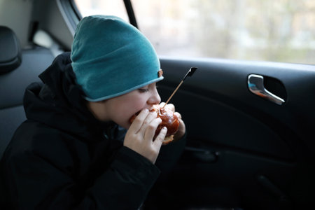 Portrait of child eating burger in carの写真素材