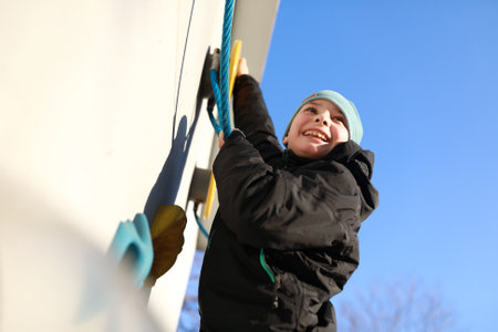 Boy climbing rope on wall at playgroundの写真素材