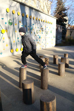 Child walking on wooden posts at playground
