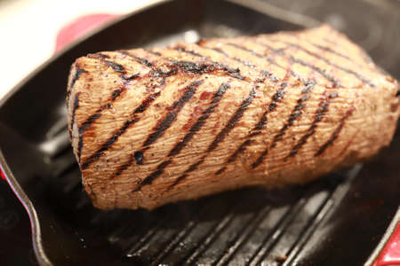 Roast beef on grill pan in kitchenの写真素材