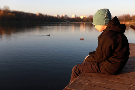 Portrait of boy by lake at sunsetの写真素材