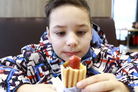 Portrait of child has hot dog in cafe at gas stationの写真素材