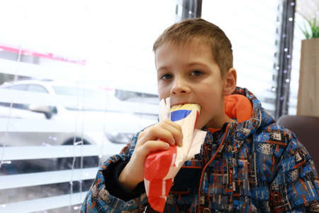 Portrait of child eating hot dog in cafe at gas stationの写真素材
