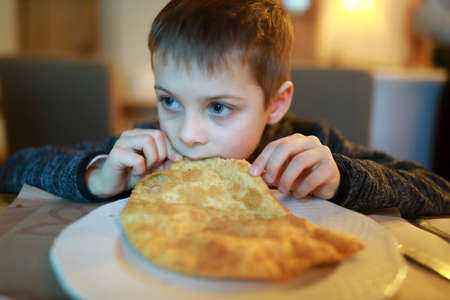 Child eating cheburek in an asian restaurantの写真素材