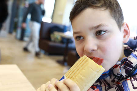 Kid eating hot dog in a restaurant