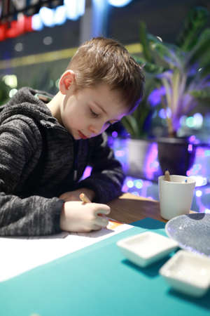 Portrait of kid drawing in a cafeの写真素材