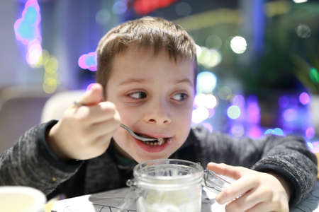 Child eating ice cream in a cafeの写真素材