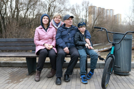 Family sitting on wooden bench in springの写真素材