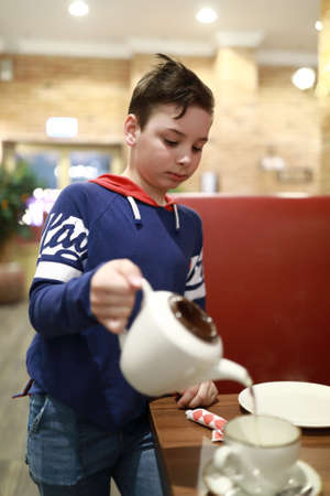 Portrait of a boy pouring tea in a restaurantの写真素材