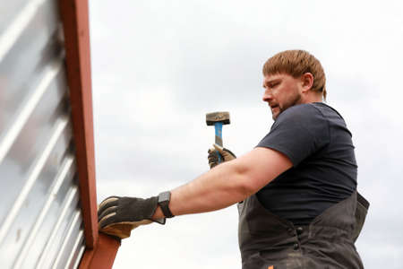 Man pounding fence post with hammer in summerの写真素材