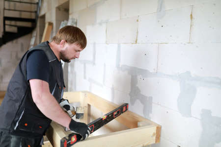 Man using level to assess levelness of tableの写真素材