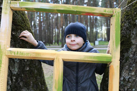 boy looking through wooden frame in parkの写真素材
