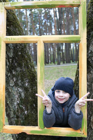 child looking through wooden frame in parkの写真素材