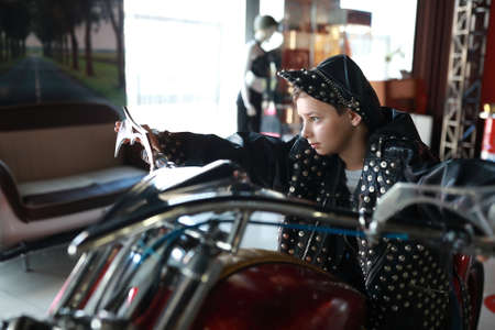 Portrait of boy in leather jacket and cap on motorcycleの写真素材