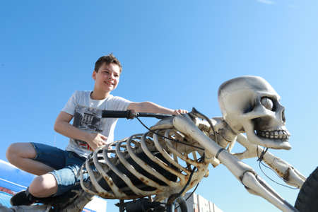 Portrait of a boy sitting on a motorcycle in the form of a skeletonの写真素材