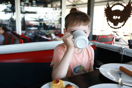 Portrait of a child drinking tea in a restaurantの写真素材