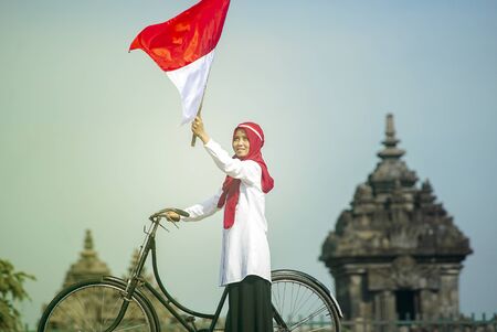 Asian Hijab flapper Indonesian flag in bicycle, Indonesian independence dayの写真素材