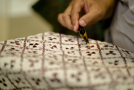 August 11 2019, Surakarta Indonesia : Close Up hand to make batik on the fabric with canting with bokeh backgroundのeditorial素材