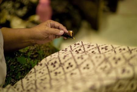August 11 2019, Surakarta Indonesia : Close Up hand to make batik on the fabric with canting with bokeh backgroundのeditorial素材