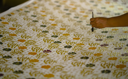 August 11 2019, Surakarta Indonesia : Close Up hand to make batik on the fabric with canting with bokeh backgroundのeditorial素材