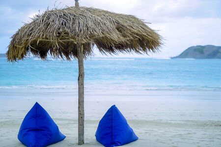 View of nice empty sandy beach with umbrella and beach chair, turquoise water in Lombok Beach