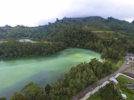 Aerial view of wild forest lake in Indonesia.  Telaga Warna with hill and foggy background in Dieng Indonesiaの写真素材